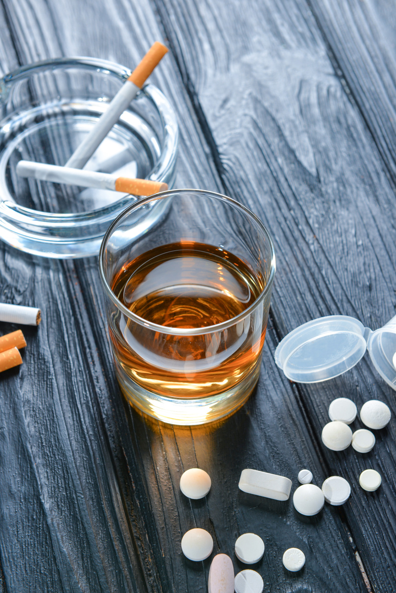 Glass of Alcohol, Cigarettes and Drugs on Table